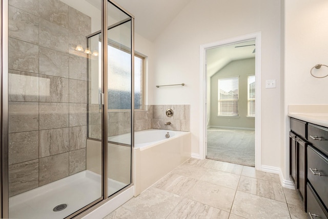 bathroom featuring baseboards, vaulted ceiling, vanity, a shower stall, and a bath