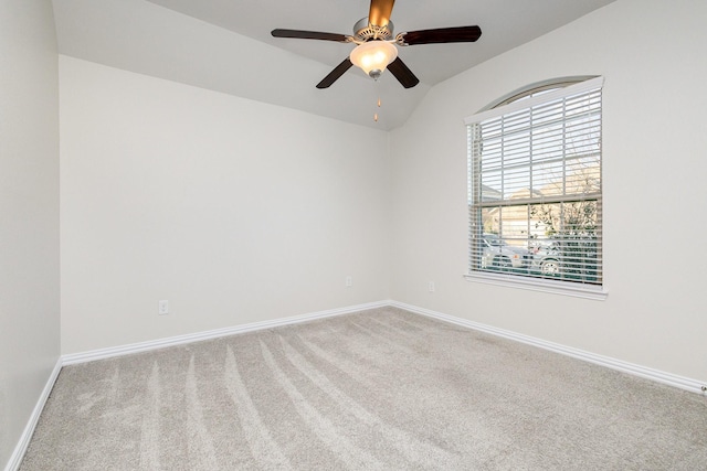 spare room with carpet floors, vaulted ceiling, baseboards, and ceiling fan