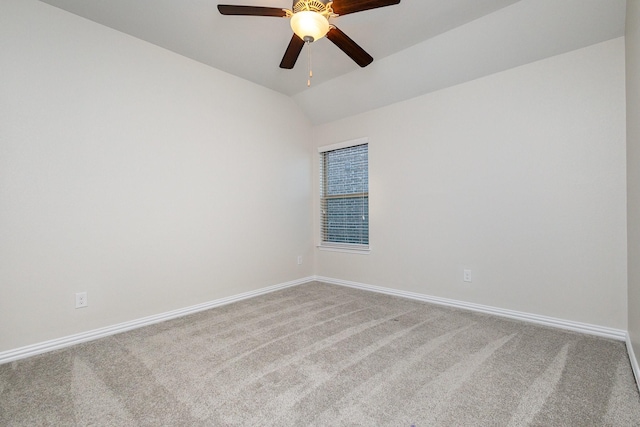 carpeted empty room with vaulted ceiling, a ceiling fan, and baseboards