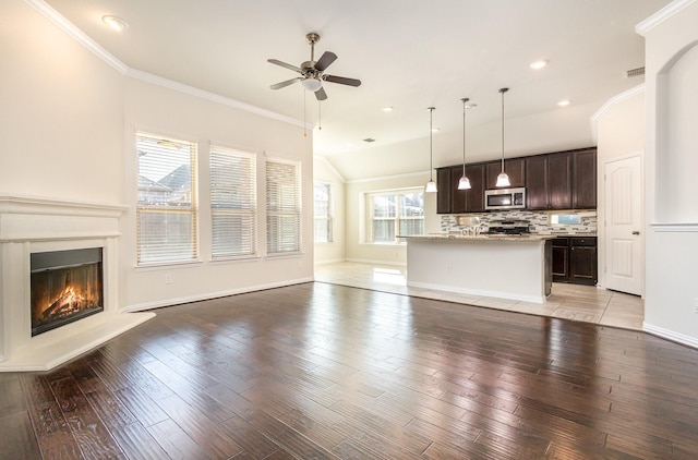 unfurnished living room with ornamental molding, a glass covered fireplace, a ceiling fan, light wood-type flooring, and baseboards