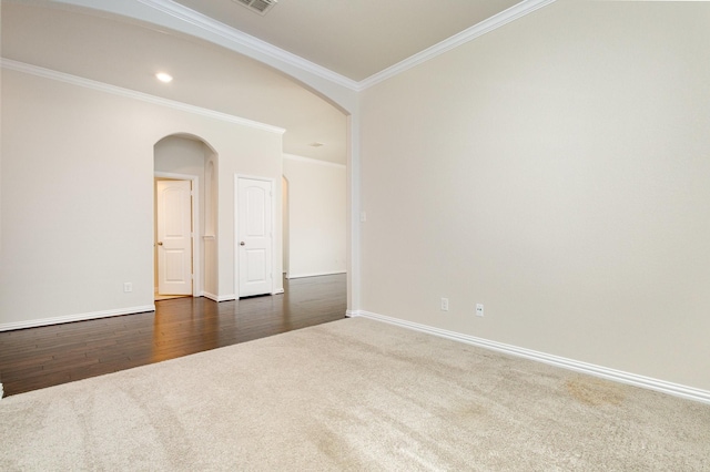 unfurnished room with arched walkways, visible vents, dark carpet, ornamental molding, and baseboards