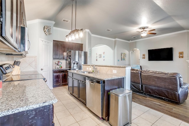 kitchen featuring stainless steel appliances, hanging light fixtures, open floor plan, a kitchen island with sink, and a sink