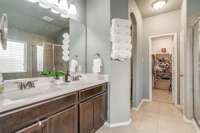 bathroom with a walk in closet, tile patterned flooring, a sink, and a shower stall