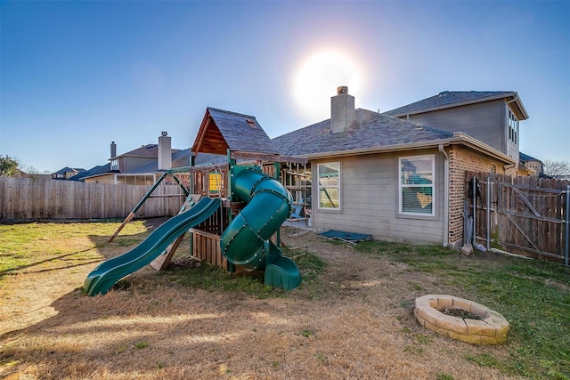 view of play area with fence, a fire pit, and a lawn