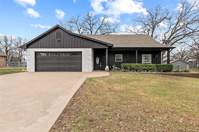 view of front of property with a garage, roof with shingles, concrete driveway, and a front yard