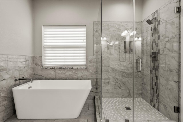 bathroom with a stall shower, a soaking tub, and tile walls