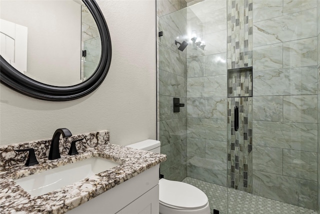 bathroom with toilet, a stall shower, a textured wall, and vanity