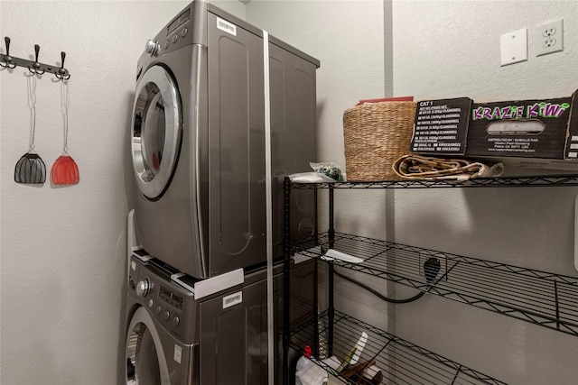 laundry area with laundry area, stacked washer / dryer, and a textured wall