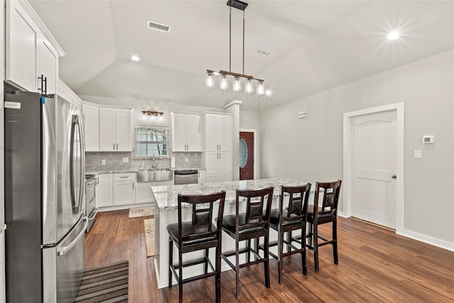 kitchen featuring a center island, visible vents, hanging light fixtures, appliances with stainless steel finishes, and white cabinetry