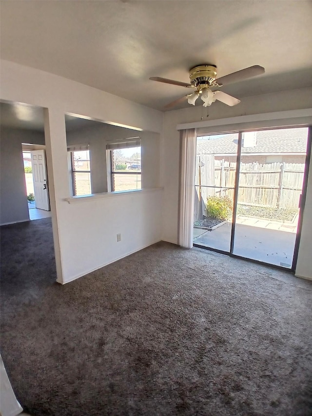 empty room with dark carpet and a ceiling fan