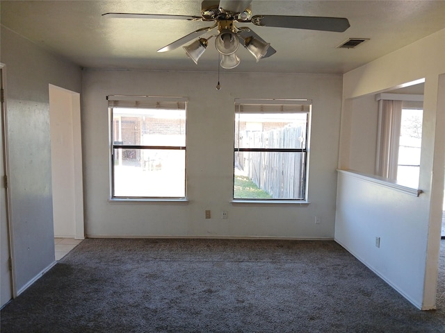 carpeted empty room with visible vents and a ceiling fan