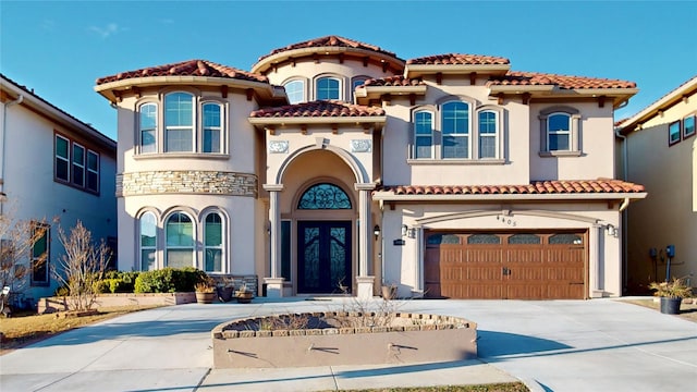 mediterranean / spanish house featuring driveway, stone siding, and stucco siding