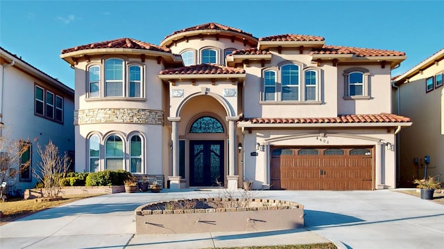 mediterranean / spanish house featuring a garage, driveway, french doors, and a tile roof