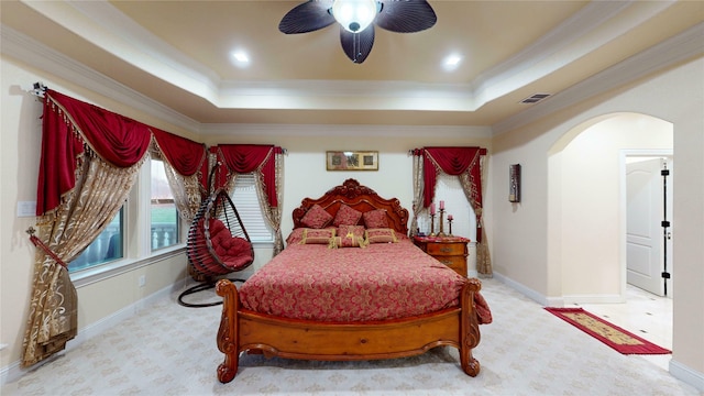 carpeted bedroom featuring visible vents, arched walkways, a tray ceiling, and ornamental molding