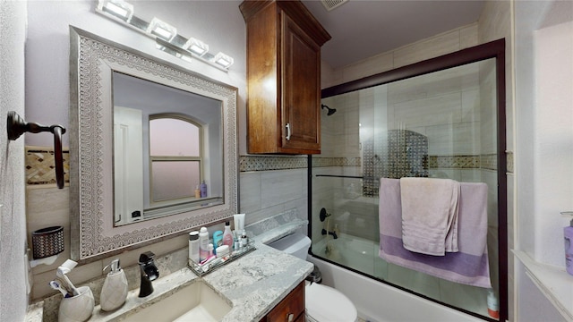 full bathroom with toilet, bath / shower combo with glass door, and vanity