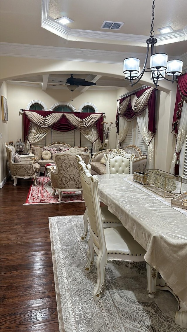 dining room featuring baseboards, ornamental molding, visible vents, hardwood / wood-style flooring, and ceiling fan with notable chandelier