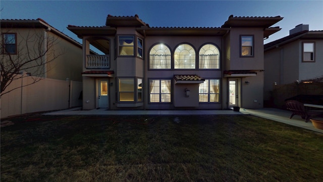back of property with a patio, a balcony, stucco siding, a tile roof, and a yard