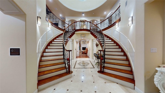entrance foyer featuring a towering ceiling, visible vents, and stairway