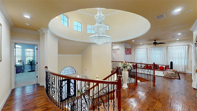 hall featuring an upstairs landing, visible vents, ornamental molding, and wood finished floors