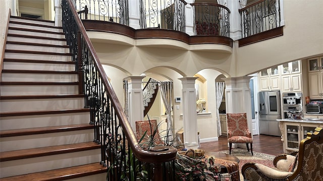interior space featuring decorative columns, arched walkways, a towering ceiling, wood finished floors, and a toaster