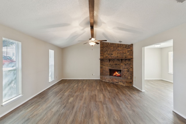 unfurnished living room featuring dark wood-style floors, a fireplace, lofted ceiling with beams, and a textured ceiling