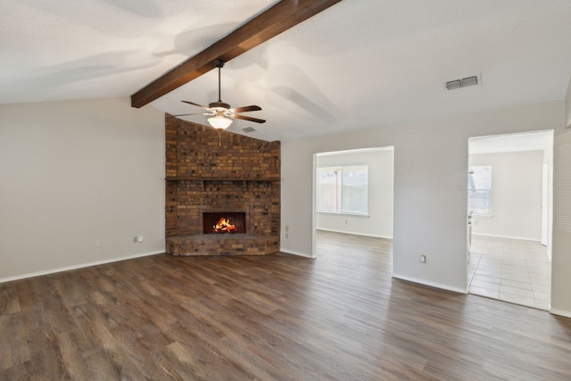 unfurnished living room with lofted ceiling with beams, a fireplace, dark wood-style floors, and visible vents