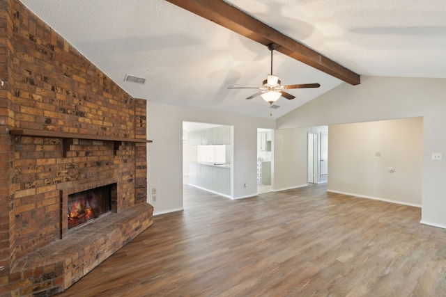 unfurnished living room with vaulted ceiling with beams, a fireplace, visible vents, and wood finished floors