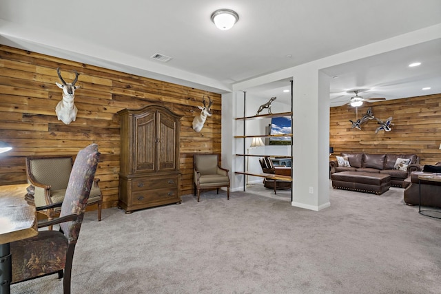 office featuring ceiling fan, wooden walls, visible vents, and light colored carpet