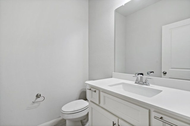 bathroom featuring vanity, toilet, and baseboards