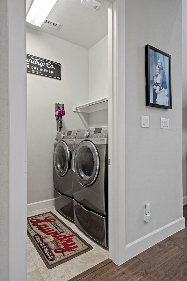 laundry area with laundry area, wood finished floors, visible vents, baseboards, and washer and dryer