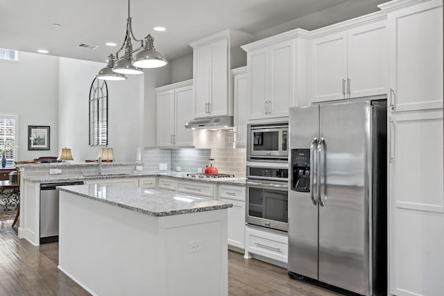 kitchen with under cabinet range hood, a peninsula, a sink, visible vents, and appliances with stainless steel finishes