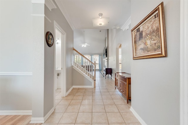 entryway featuring arched walkways, stairway, baseboards, and light tile patterned floors