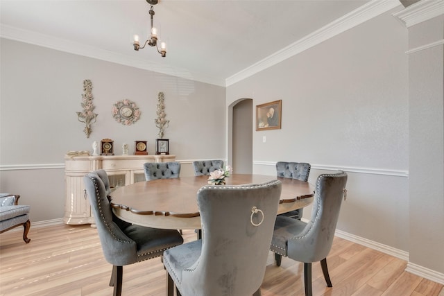 dining area with arched walkways, a chandelier, baseboards, ornamental molding, and light wood finished floors