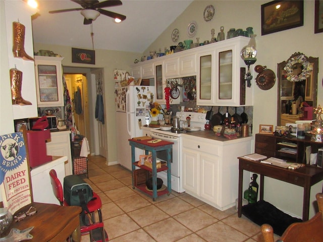 kitchen featuring lofted ceiling, white appliances, light tile patterned floors, and white cabinetry