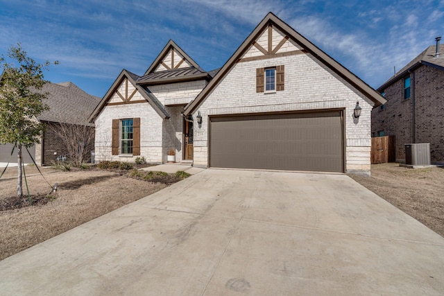 view of front facade with brick siding, central air condition unit, concrete driveway, a standing seam roof, and metal roof