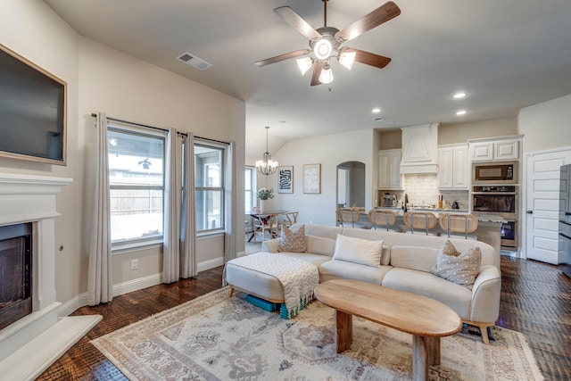 living area featuring visible vents, dark wood finished floors, arched walkways, a fireplace with raised hearth, and baseboards