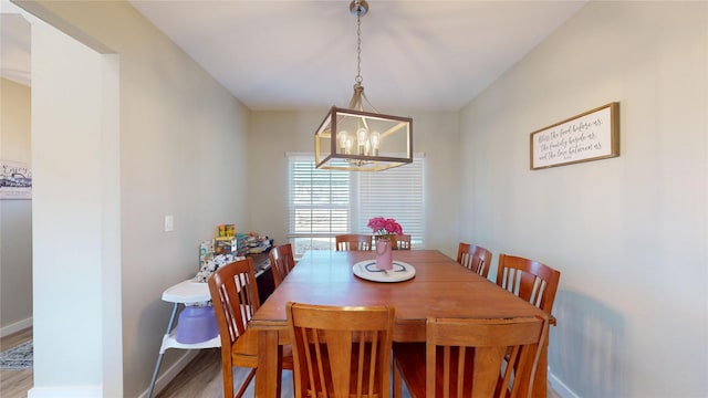 dining space with baseboards, a notable chandelier, and wood finished floors