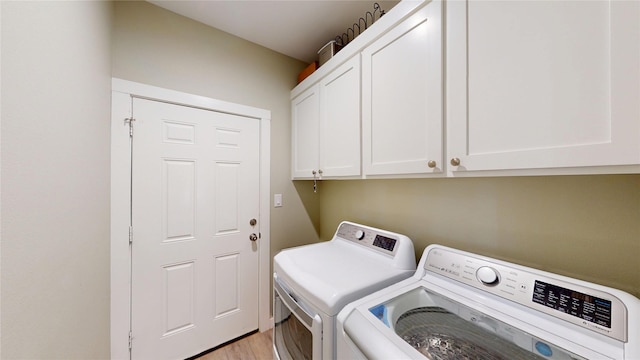 clothes washing area featuring light wood finished floors, independent washer and dryer, and cabinet space