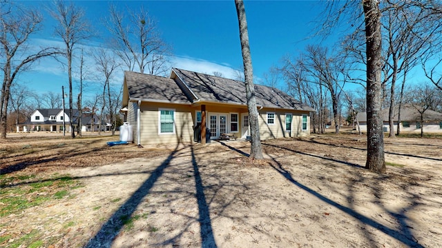 rear view of house with french doors, roof with shingles, and driveway