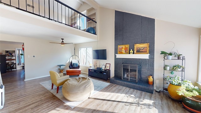 living room with high vaulted ceiling, a brick fireplace, baseboards, and wood finished floors