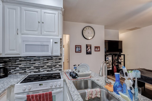 kitchen featuring white appliances, visible vents, decorative backsplash, white cabinetry, and a sink