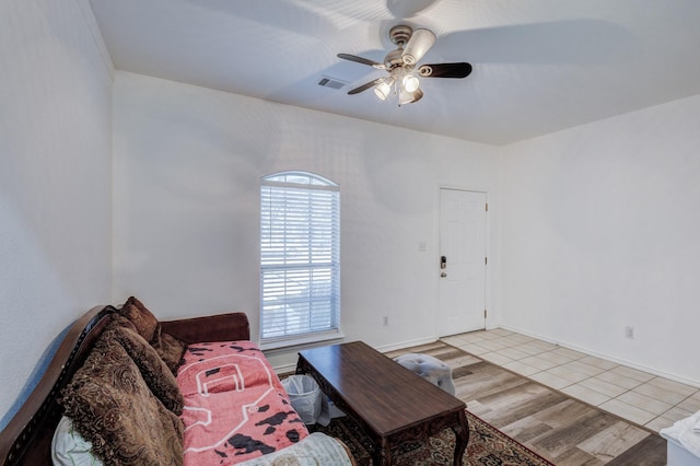 living room with ceiling fan, visible vents, light wood-style flooring, and baseboards