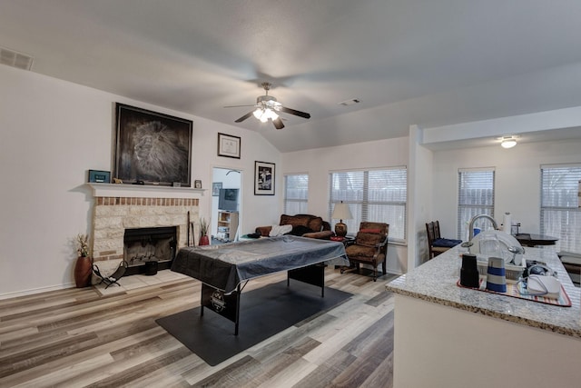 playroom with visible vents, vaulted ceiling, light wood-style flooring, and a fireplace