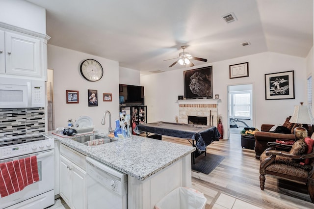 kitchen with white appliances, white cabinetry, a sink, and open floor plan