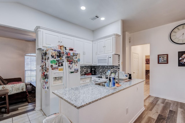 kitchen with white appliances, tasteful backsplash, visible vents, light stone countertops, and white cabinetry