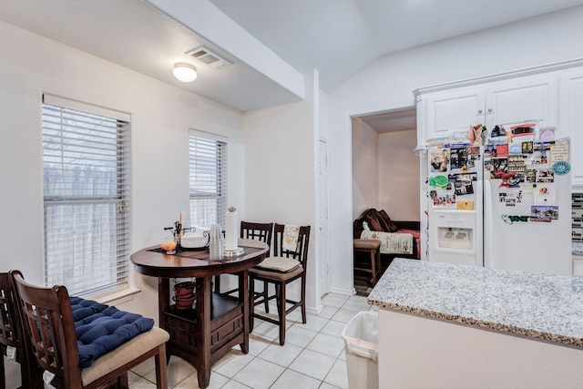 dining area with visible vents, vaulted ceiling, and light tile patterned flooring