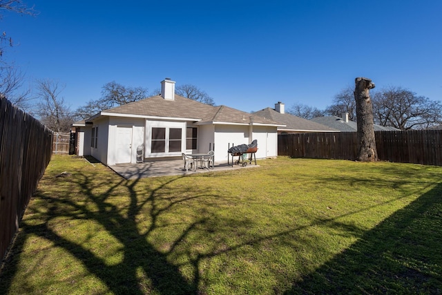 back of property with stucco siding, a fenced backyard, a patio, and a yard