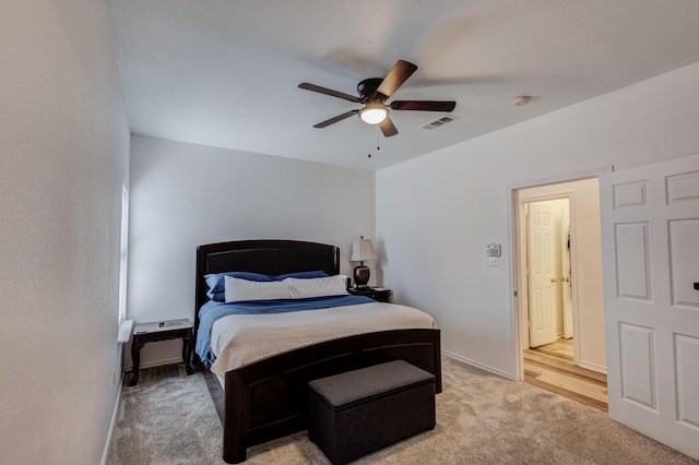 bedroom with light carpet, ceiling fan, visible vents, and baseboards