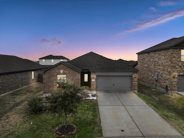 view of front of house featuring an attached garage, a shingled roof, concrete driveway, and brick siding