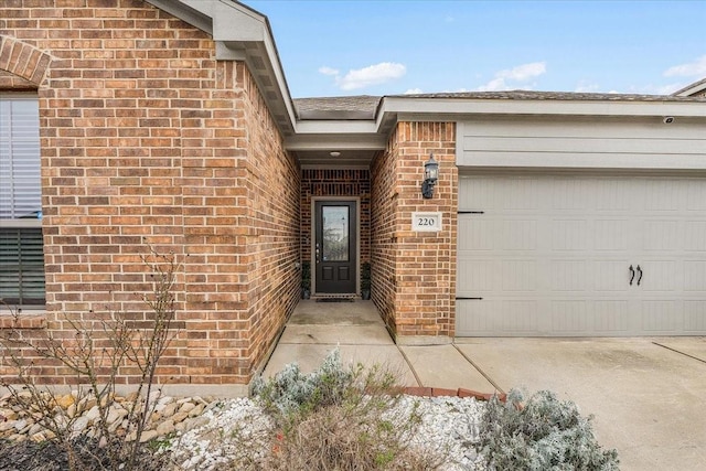 doorway to property featuring a garage and brick siding